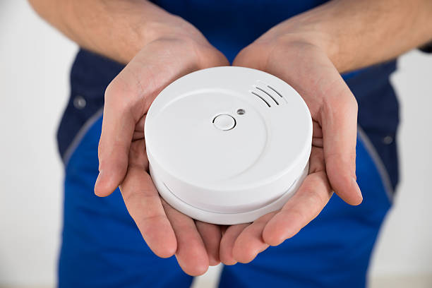 Close-up Of Male Electrician Hand Holding Smoke Detector
